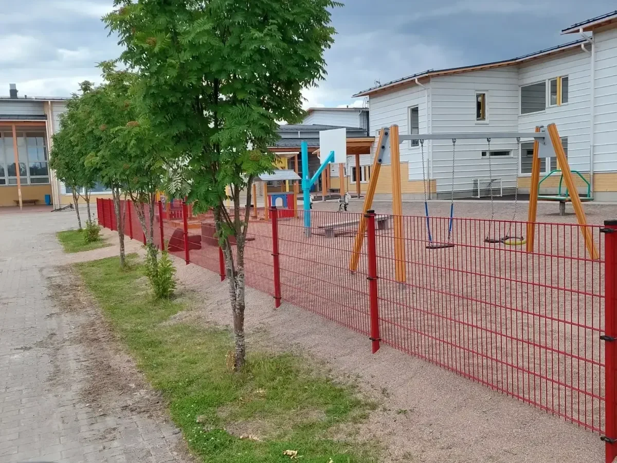 Pulverimaalattu metalliverkkoaita päiväkodin pihalla tuo turvaa ja rajaa leikkialueen selkeästi
