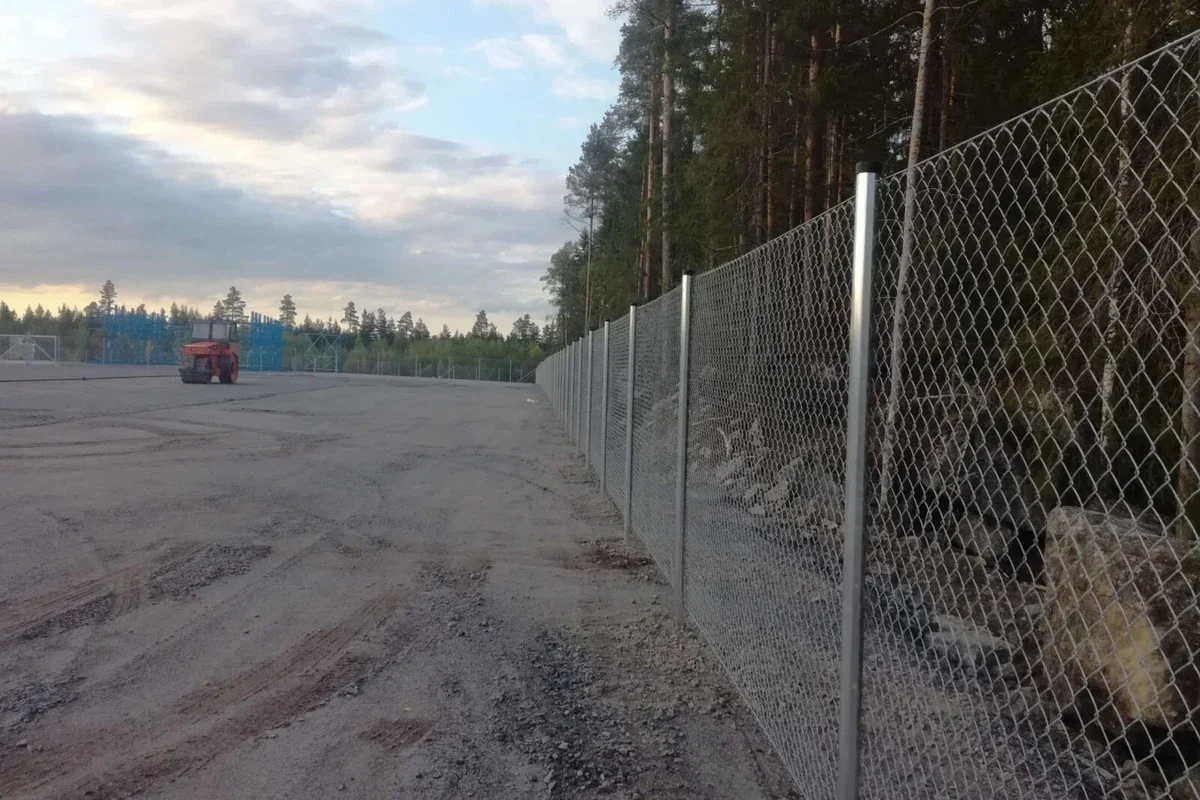 Sinkitty panssariverkkoaita rajaa laajan teollisuusalueen metsän laidassa.